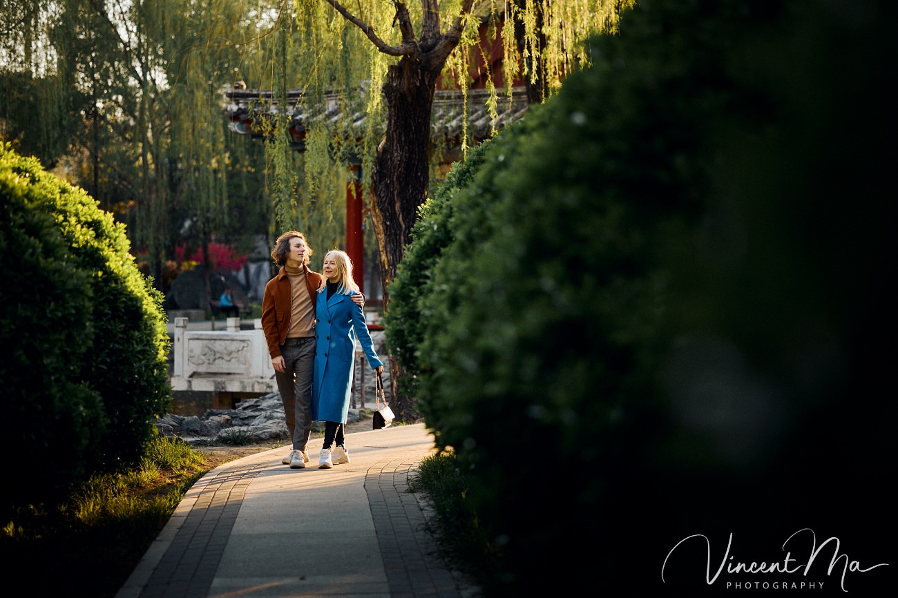 Family travel photography in Beijing featuring traditional red walls and golden hour sunlight.