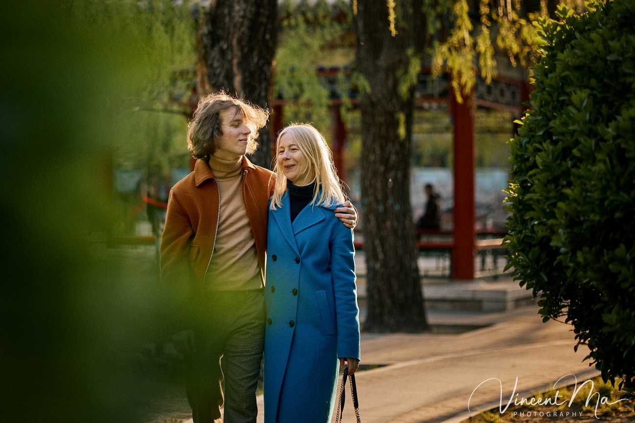 Family travel photography in Beijing featuring traditional red walls and golden hour sunlight.