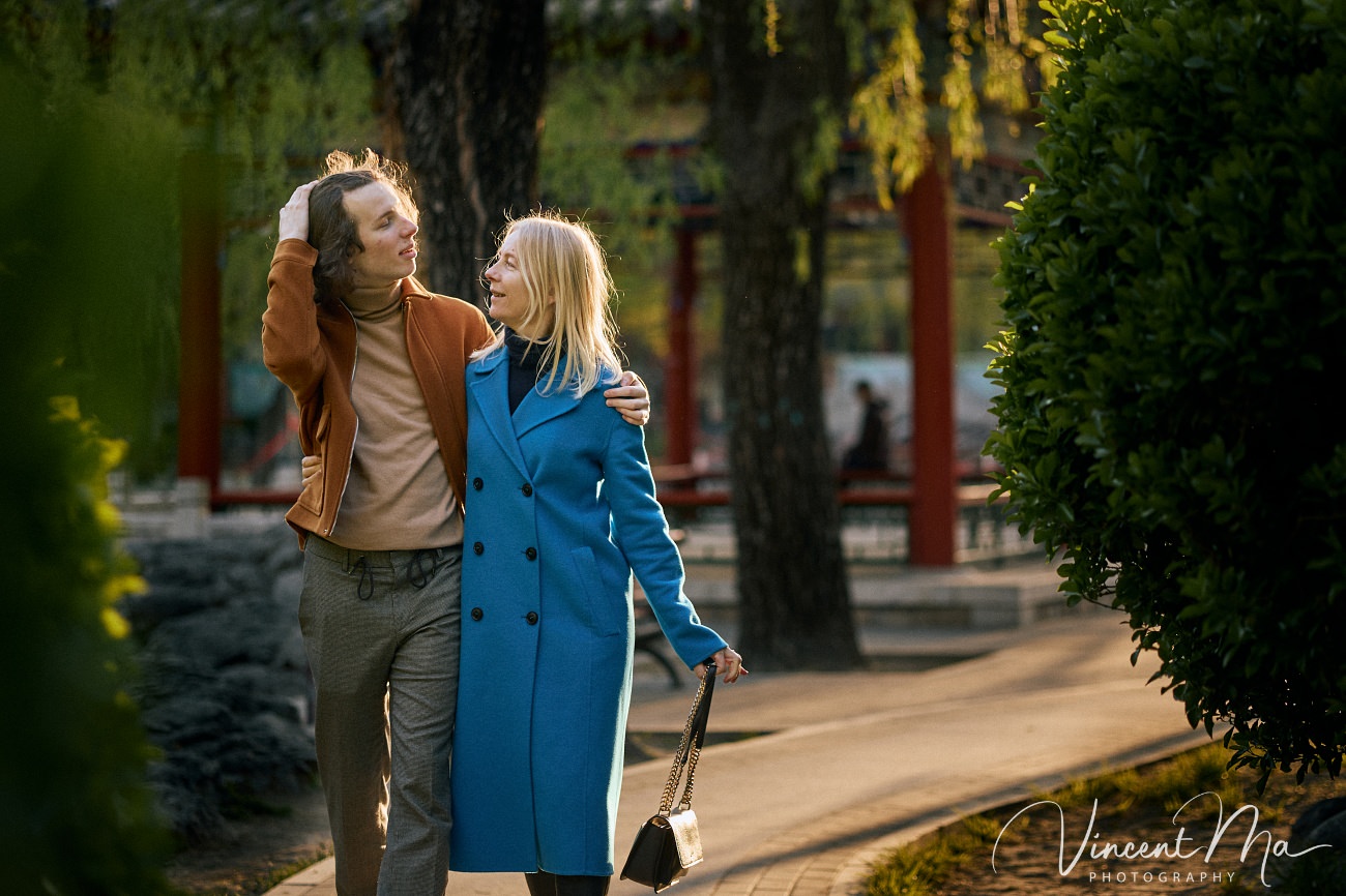 Family travel photography in Beijing featuring traditional red walls and golden hour sunlight.