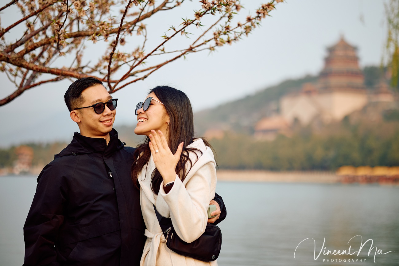 Breathtaking moment of a secret proposal at the Summer Palace, Beijing. A man on one knee amidst spring flowers and ancient imperial architecture. Captured by Beijing photographer Vincent Ma.