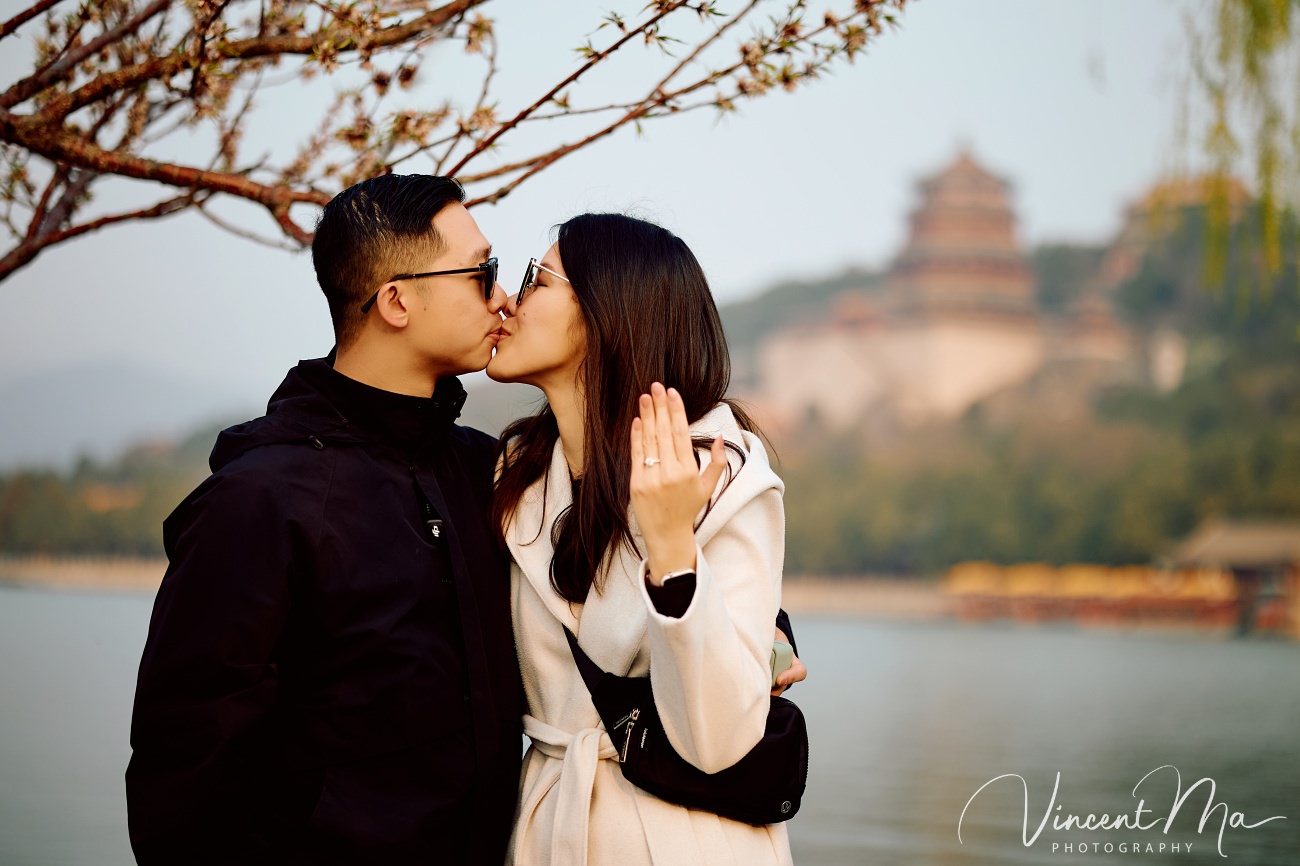 Breathtaking moment of a secret proposal at the Summer Palace, Beijing. A man on one knee amidst spring flowers and ancient imperial architecture. Captured by Beijing photographer Vincent Ma.