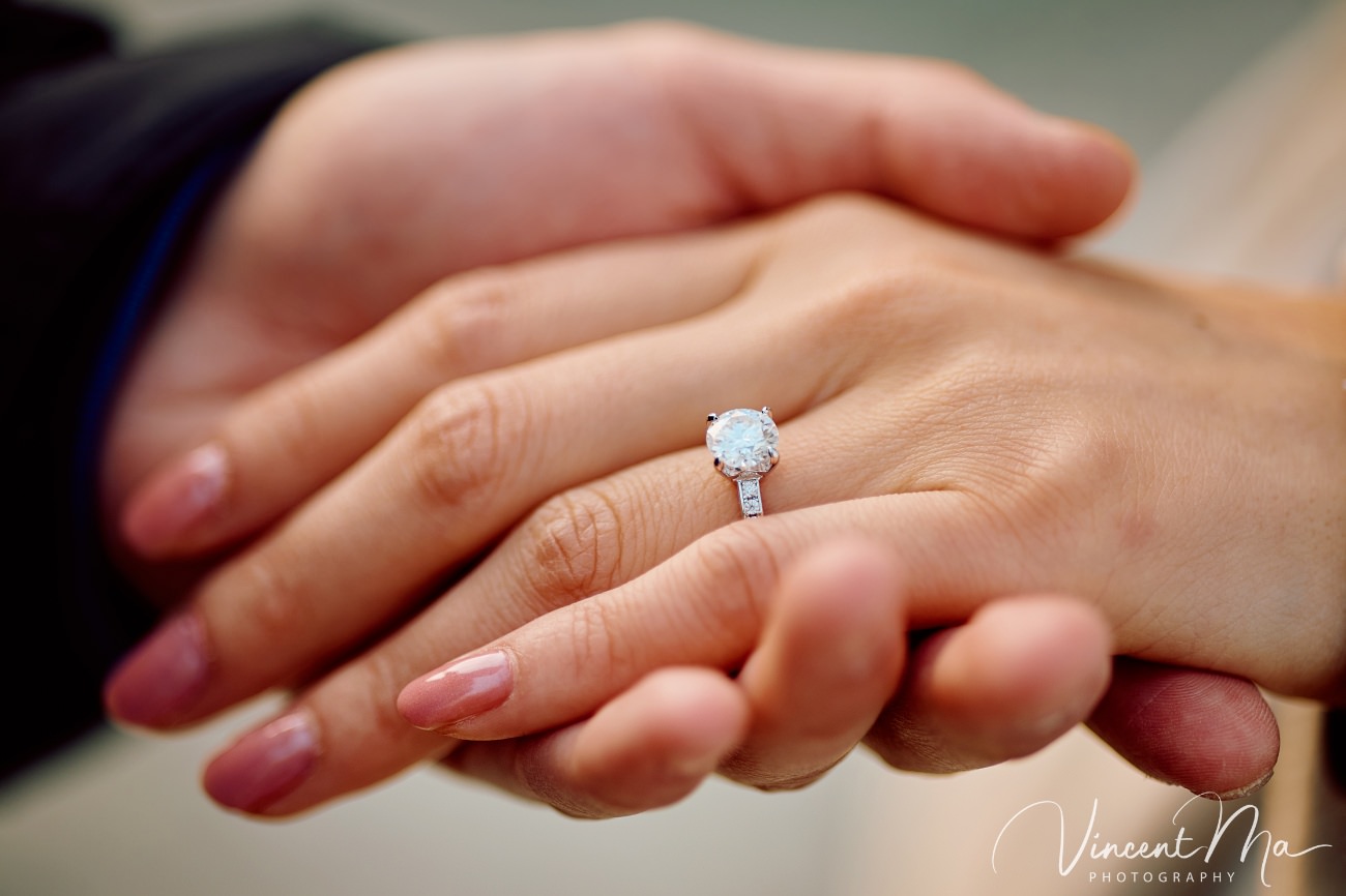 Close-up of an engagement ring held against a backdrop of spring magnolias and cherry blossoms at the Summer Palace, Beijing. Symbol of love in the heart of China.