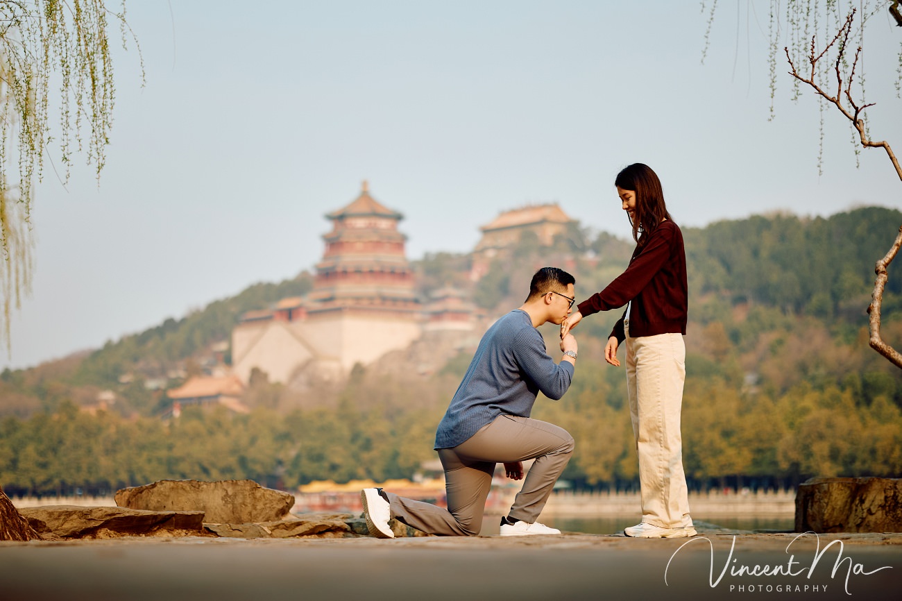 Breathtaking moment of a secret proposal at the Summer Palace, Beijing. A man on one knee amidst spring flowers and ancient imperial architecture. Captured by Beijing photographer Vincent Ma.