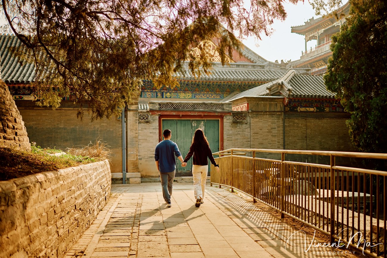Engaged American couple walking through blooming cherry blossoms and Magnolia at the Summer Palace. High-end cinematic beijing photoshoot experience.