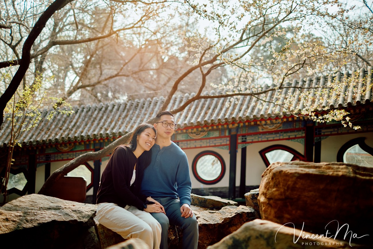 Engaged American couple walking through blooming cherry blossoms and Magnolia at the Summer Palace. High-end cinematic beijing photoshoot experience.