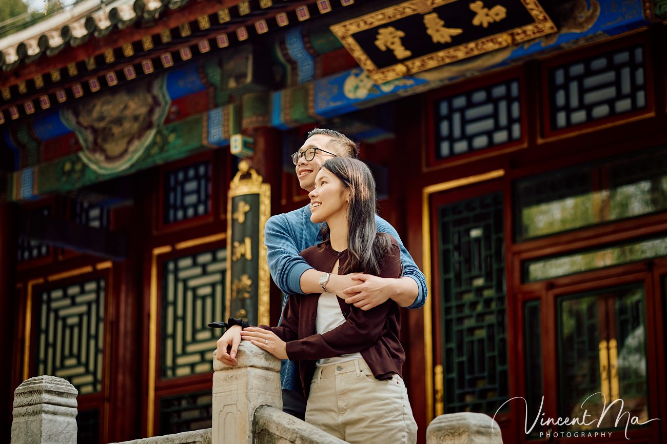 A cinematic capture of a secret proposal at the Summer Palace, Beijing. The couple is framed by blooming cherry blossoms and magnolias with the Tower of Buddhist Incense in the background. Professional photography by Vincent Ma for an American couple's first trip to China.