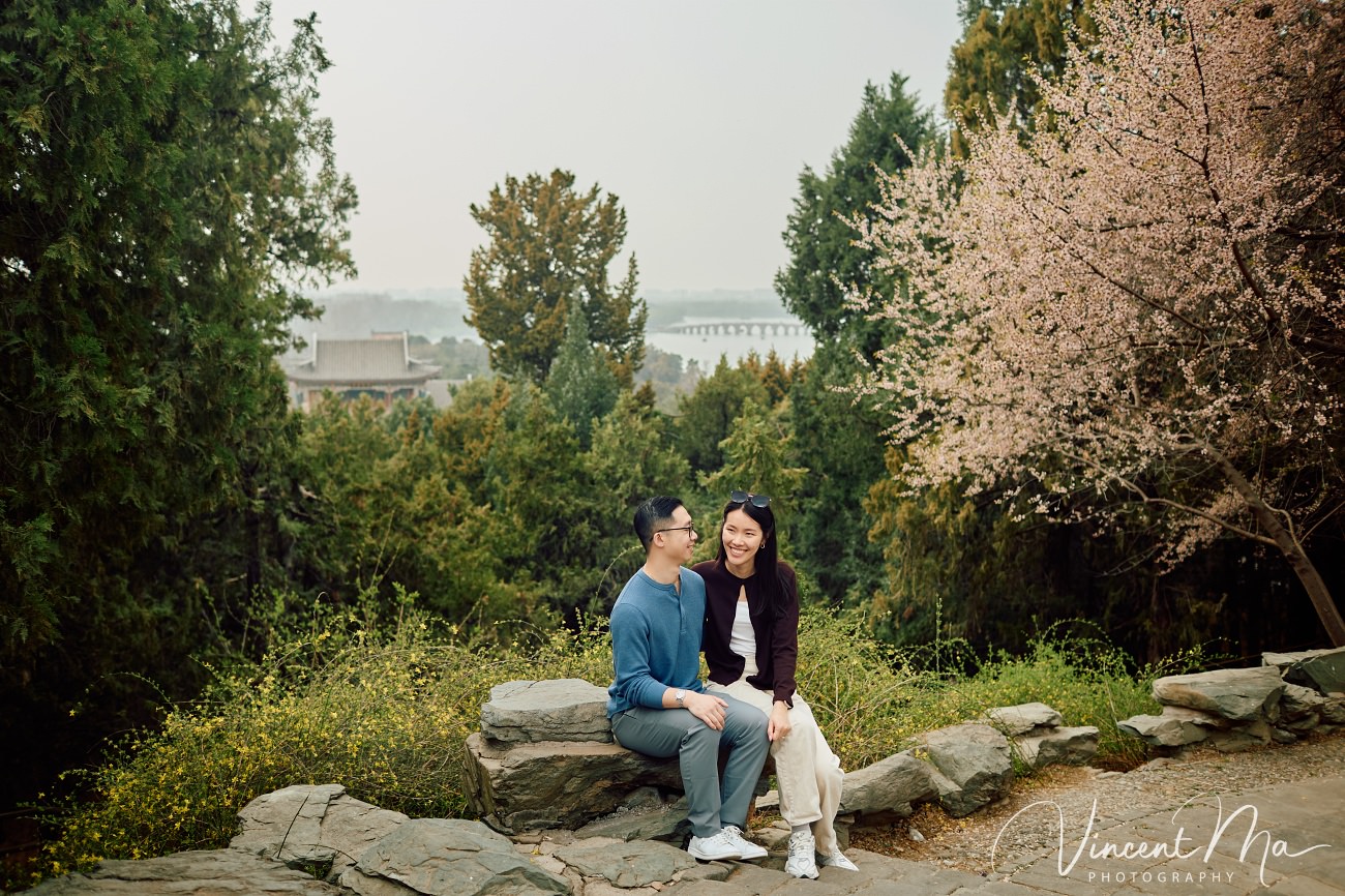 Engaged American couple walking through blooming cherry blossoms and Magnolia at the Summer Palace. High-end cinematic beijing photoshoot experience.