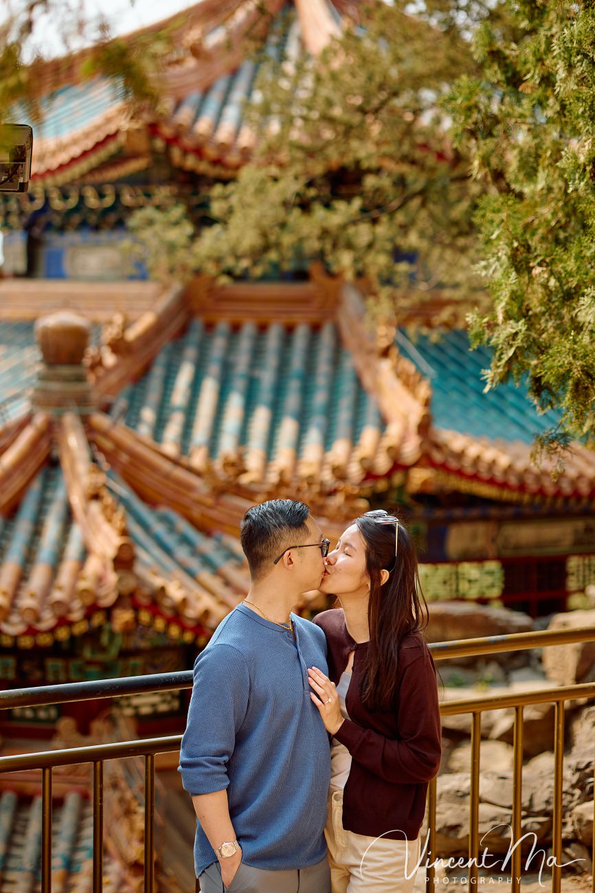 A cinematic capture of a secret proposal at the Summer Palace, Beijing. The couple is framed by blooming cherry blossoms and magnolias with the Tower of Buddhist Incense in the background. Professional photography by Vincent Ma for an American couple's first trip to China.