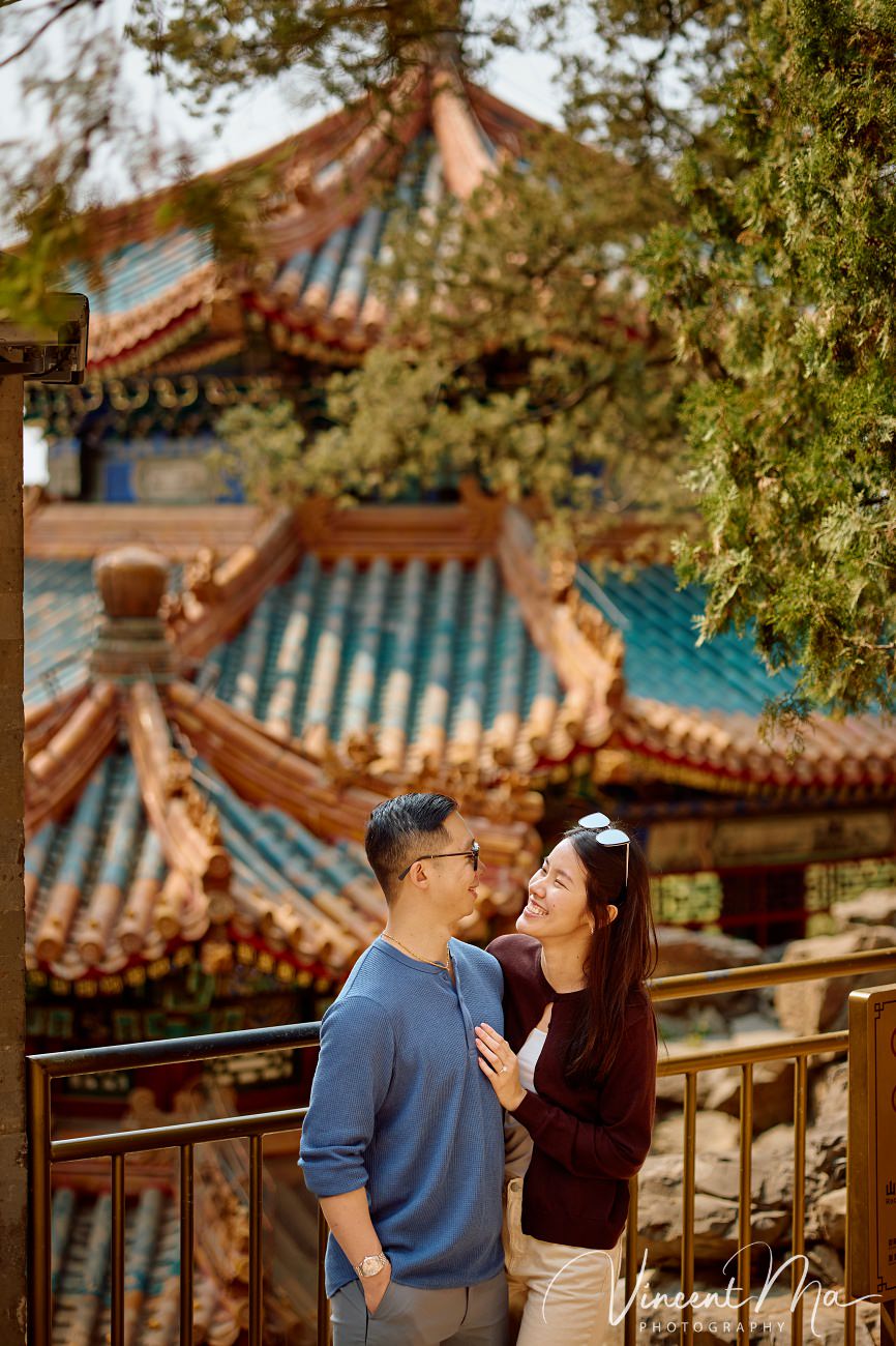 A cinematic capture of a secret proposal at the Summer Palace, Beijing. The couple is framed by blooming cherry blossoms and magnolias with the Tower of Buddhist Incense in the background. Professional photography by Vincent Ma for an American couple's first trip to China.
